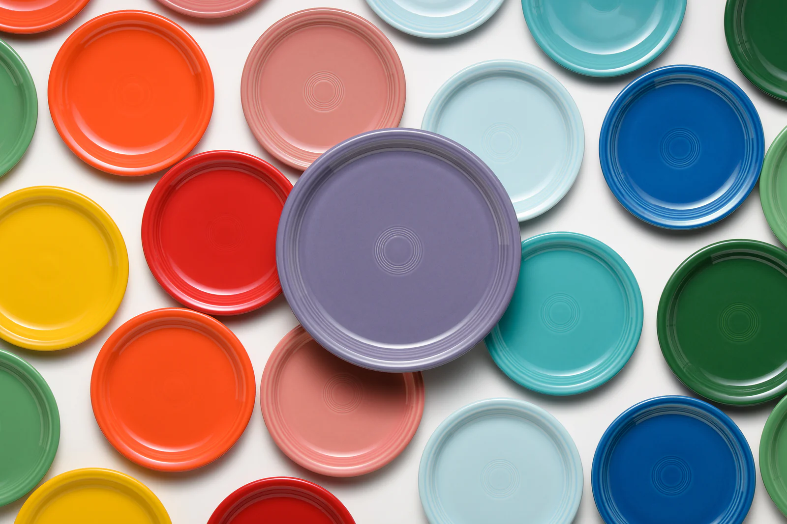 A colorful arrangement of various plates in shades of red, green, blue, yellow, and purple, with one purple plate in the center.